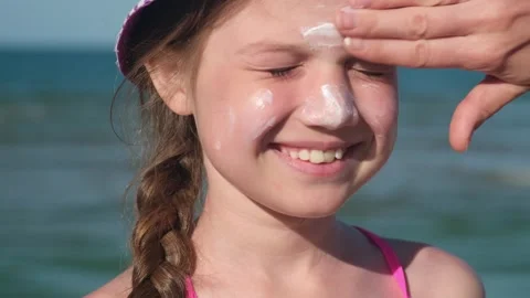Close up mother applying protective sunscreen on daughter at beach Vídeo Stock 339284900