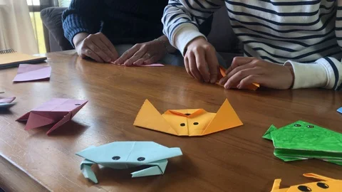 Close-up of a mother with her son while they are at home doing origami crafts Stock Footage 127746253