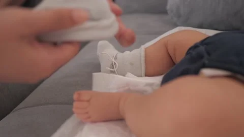 Close up mother putting socks on her newborn baby. Little moving legs of a child Stock Footage 166528816