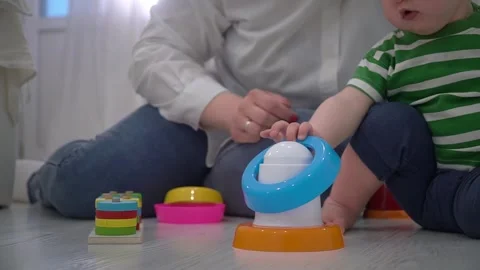 Close-up of a mother with a toddler child assembling a children's pyramid toy Stock Footage 299737189