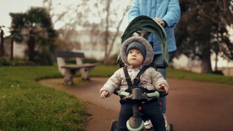 Close-up of a mother's hands carrying a tricycle stroller with a baby Stock Footage 296180853