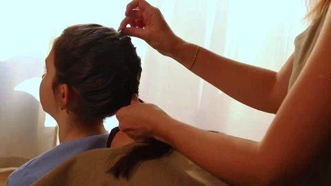 Close-up of mother's hands weaving braid in daughter's hair. Beauty routine Stock Footage 309525876