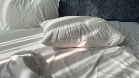 Close-Up motion above Empty Disheveled Bed with White Pillows Against Blue Stock Footage 342891563