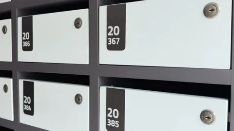 Close-up motion along multiple white metal mailboxes with numeric labels and Vidéo 314353995