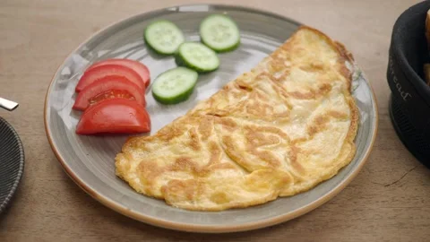 Close-up motion of folded omelette with sliced tomatoes and cucumber on plate Stock Footage 332891729