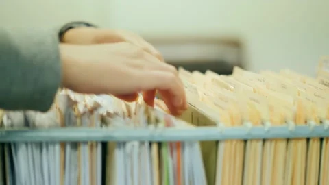 Close up motion of hands searching through yellow hanging files in a filing.. Stock Footage 334828835