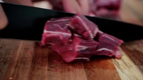 Close up motion of person cutting raw beef meat into small cubes on a woode.. Stock Footage 339651833