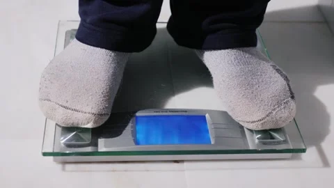 A close up motion shot of a person stepping on a digital scale to check wei.. Stock Footage 334641480