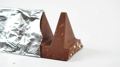 Close up motion of triangular chocolate bar with nuts and foil packaging on.. Stock Footage 332627018