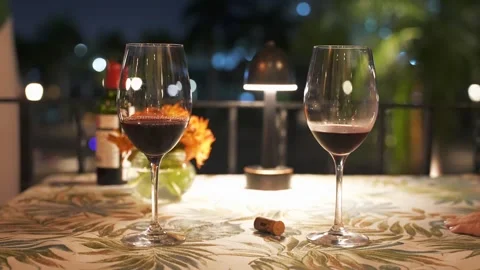 Close up motion of two red wine glasses on a table illuminated by lamp. Romantic Stock Footage 274772178