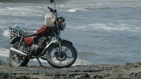 Close up of motorcycle on beach with waves during day time Stock Footage 143016567