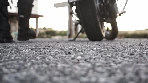 Close-up of motorcycle boots getting on a motorcycle with blur in the background Stock Footage