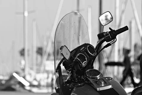 Close-up of motorcycle controls and windshield with marina masts in the Stock Photos