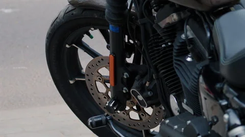 Close up of a motorcycle front wheel, tire, brake disc, and engine details Stock Footage 335464923