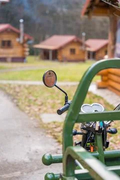 Close-up of a motorcycle handle with rustic log cabins in the Czech forest Stock Photos