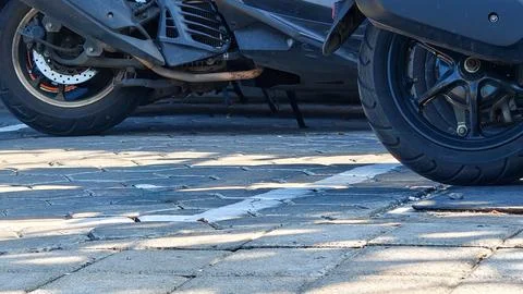 Close-Up of Motorcycle Wheels and Engine Parked on Paved Ground 写真素材