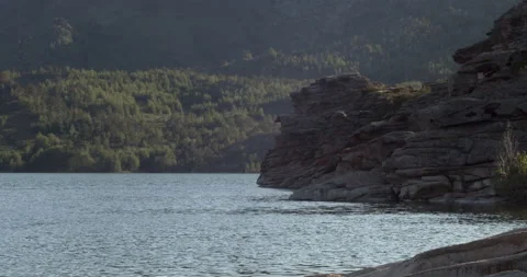 Close up. Mountain lake surrounded by rocks and pine-covered hills Stock Footage 139528193