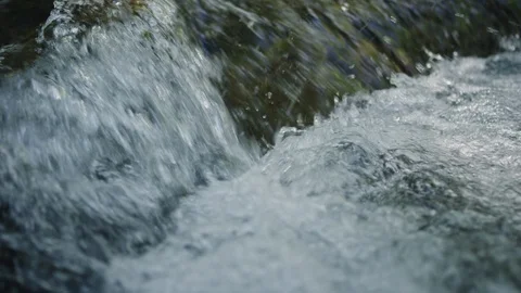Close up mountain stream flows, crashes, and bubbles along in slow motion Stock Footage 127461689