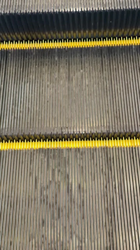 Close-up of Moving Metal Escalator Steps with Yellow Safety Lines Stock-Footage 345099901