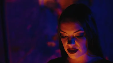 In a close-up moving shot, a beautiful witch, with dark makeup and dressed in a Stock Footage 258656732