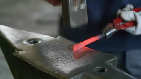 Close-Up Moving Shot of Blacksmith Hammering Hot Metal on Anvil Stock Footage 313849782