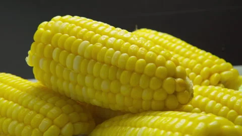Close-up moving view of freshly boiled yellow corn cobs on dark background Video stock 348548886