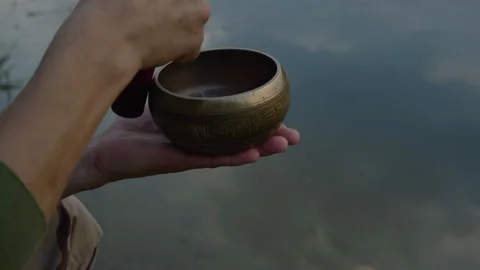 Close-up, mud hands holding tibetan singing bowl and extracting sounds from it Stock Footage 258859063