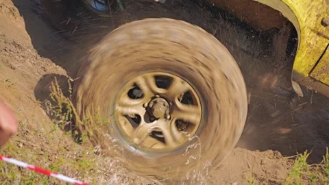 Close-up of a muddy SUV wheel spinning and kicking up clods of soi Stock Footage 288509277