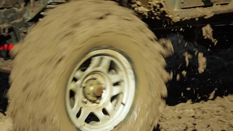 A close-up of the muddy tires of an SUV kicking up chunks of mud Stock Footage 344875928