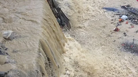 Close up of muddy water flowing over a concrete barrier close-up view Видео 342586642