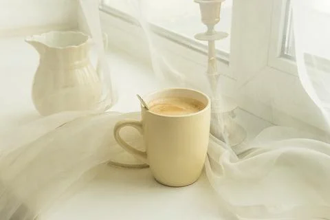 Close up for mug of coffee on a white table near a window Stock Photos