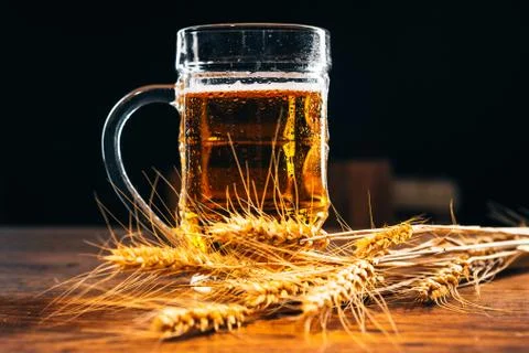 Close-up mug of light beer with ears of wheat on the wooden table Stock Photos
