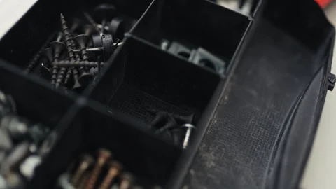 Close-up of a multi-bit screwdriver, nails, and boots in a plastic organizer, ho Stock Footage 335644116