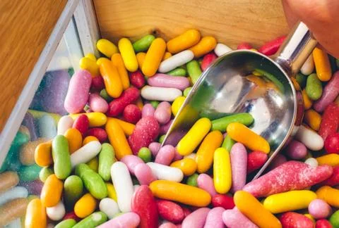 Close-up of multi-colored candy sticks / sweets with a hand filling a scoop Stock Photos