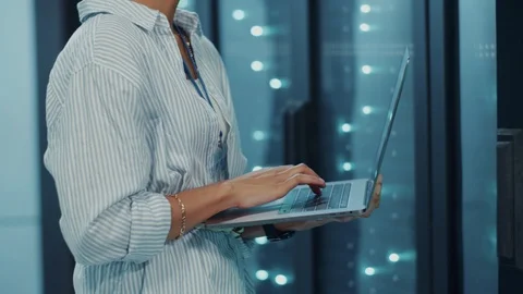 Close-up multi-ethnic woman programmer coding on laptop at server cabinet Stock Footage 121225351