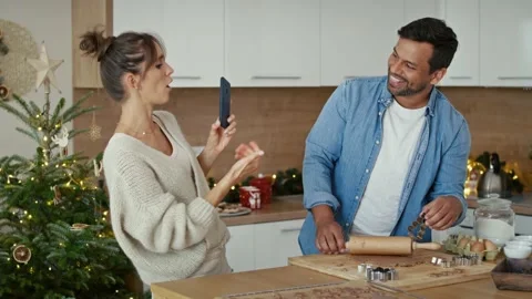 Close up of multi ethnicity couple making a gingerbreads and using mobile phone  Stock Footage 218773192