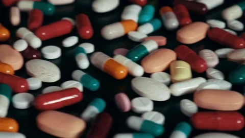 Close up of multicolor pills and capsules on a black table Stock Footage 105853364