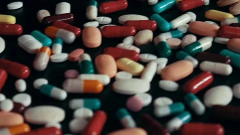 Close up of multicolor pills and capsules on a black table Stock Footage 105853397