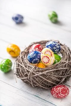 Close-up multicolored easter eggs in basket on wooden table Stock Photos