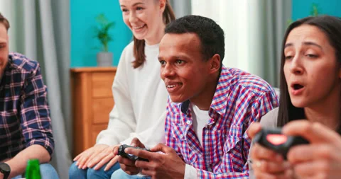Close up of multinational group of college students sit on the couch and play Stockbeeldmateriaal 152387900