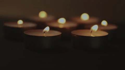 Close-up of multiple burning tea light candles in a dark cozy atmosphere Video stock 338191778