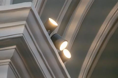 Close-up of multiple elongated, modern ceiling lights against a decorative ti Stock Photos