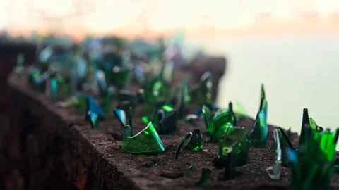 Close up of multiple green broken glass shards on the top of a brick wall with a Stock Footage 311483481