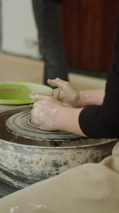 Close-up of multiple hands covered in wet clay working together on a pottery Stock Footage 303515008