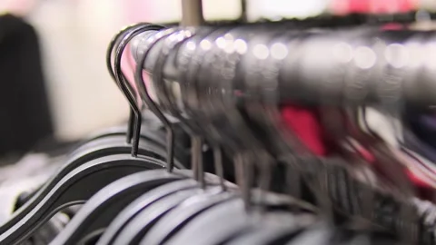 Close-up of multiple hangers with assorted clothing on a rotating rack in a Stock-Footage 295777329