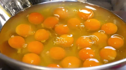 Close-up of multiple raw egg yolks in a large metal bowl, preparation for baking Stock Footage 331772193