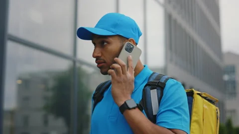 Close-Up of a Multiracial Male Courier Calling a Customer, Standing Near the Stock Footage 237469848