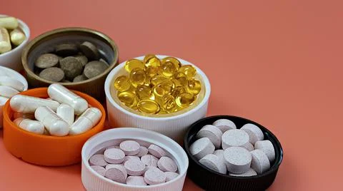 Close-up of multivitamin biologically active supplements on coral background Foto stock