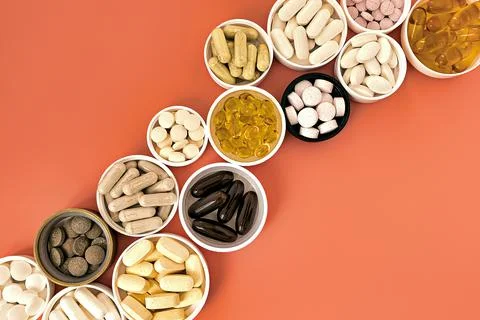 Close-up of multivitamin biologically active supplements on coral background 库存照片