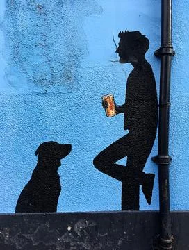 Close up mural of man drinking beer with his dog in black on blue wall Stock Photos